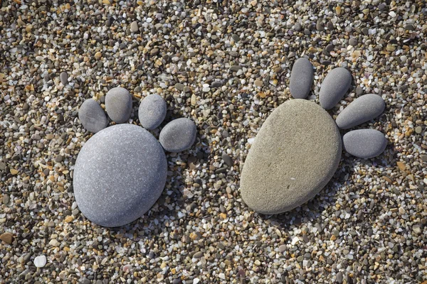 Två spår fötter gjorda av en sten sten på stranden bakgrund — Stockfoto