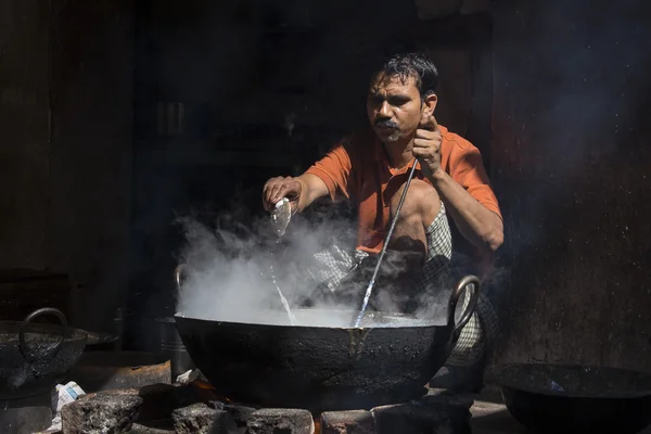 El hombre cocina en el viejo wok el fuego en el mercado callejero. Pushkar, India — Foto de Stock