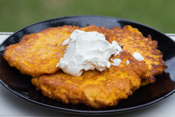 Aardappel en wortel pannenkoeken met zure room — Stockfoto