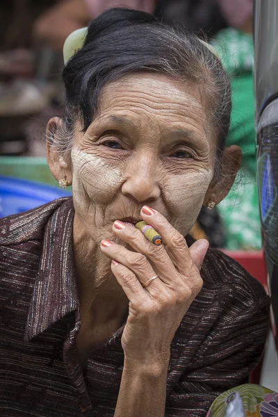 Äldre dam som sitter på gatan röka en cigarett. Yangon, Myanmar — Stockfoto