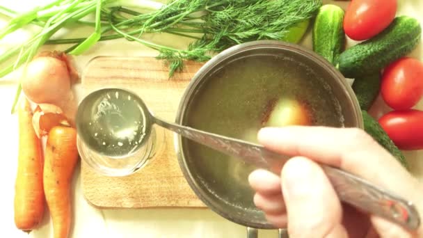 Man giet de kippenbouillon in een glazen pot — Stockvideo