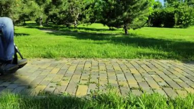 Engelli biri parkta tekerlekli sandalyeye biniyor.