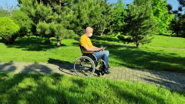 Homme chauve handicapé dans un masque jouant ou étudiant dans une tablette — Video