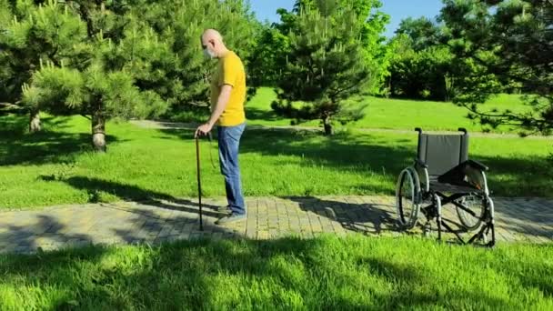 Una persona discapacitada camina en un parque con una máscara durante una pandemia — Vídeos de Stock