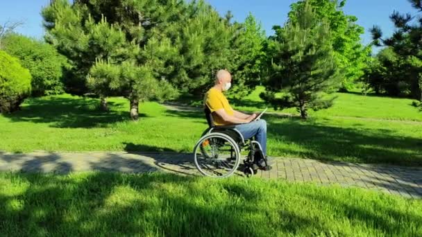 Une personne chauve handicapée dans un masque organise une vidéoconférence dans le parc — Video