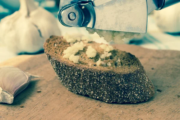 Garlic press on a piece of bread — Stock Photo, Image