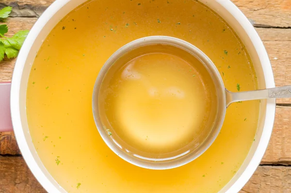 Cuillère avec bouillon dans la casserole avec fond de bouillon — Photo