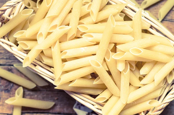 Dry pasta in a wicker basket on the table — Stock Photo, Image