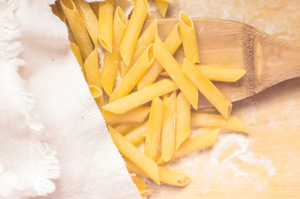 Dry pasta on a wooden scoop — Stock Photo, Image