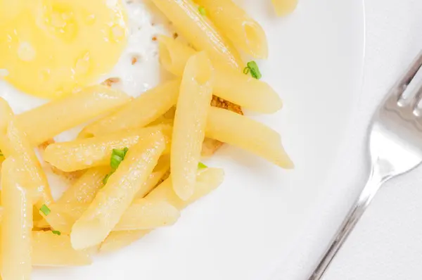 Penne pasta edge of the plate with a fried egg yolk — Stock Photo, Image