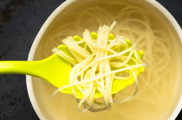 Spoon spaghetti pasta pulls out of the pan with water — Stock Photo, Image