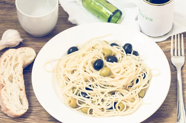 Set the table a dish of spaghetti with olives and oil — Stock Photo, Image