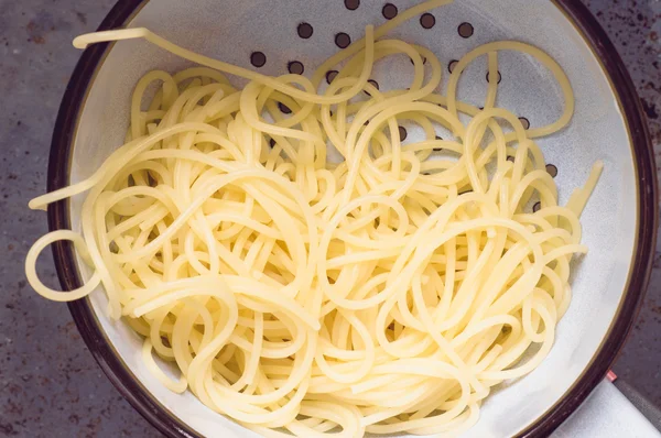 Spaghetti pasta drained in old colander — Stock Photo, Image
