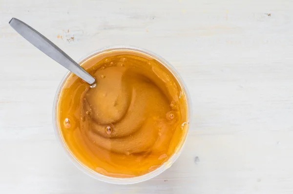 Tarro de plástico denso miel con una cuchara — Foto de Stock