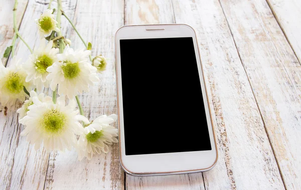 Smart phone and fresh flowers on white wood table — Stock Photo, Image