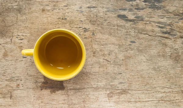 Tazza di caffè gialla su vecchio tavolo di legno — Foto Stock