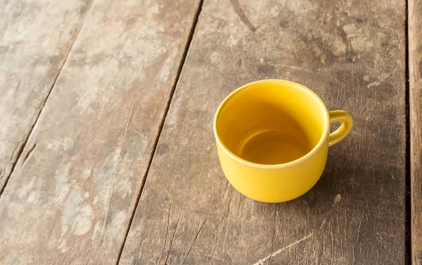 Yellow coffee cup on old wooden table — Stock Photo, Image