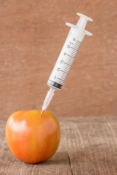 Tomate fraîche et seringue sur table en bois — Photo