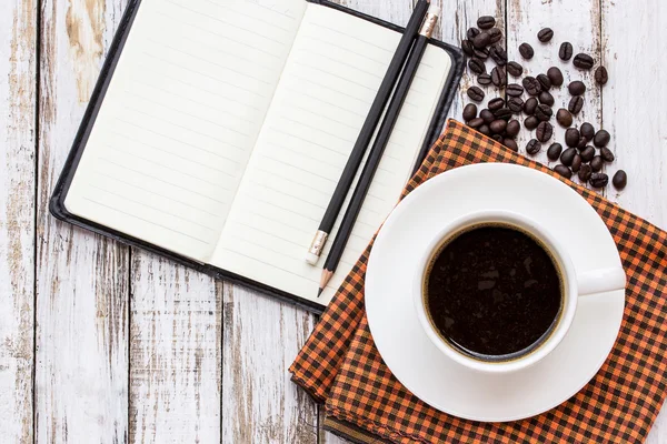 Kaffekopp och anteckningsbok på vita träbord — Stockfoto