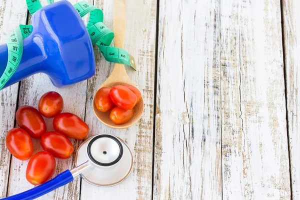 Mavi stetoskop ve Beyaz ahşap t kırmızı domates halterle — Stok fotoğraf