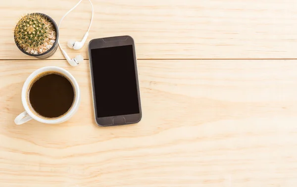 Koffiekopje en smartphone op houten tafel — Stockfoto