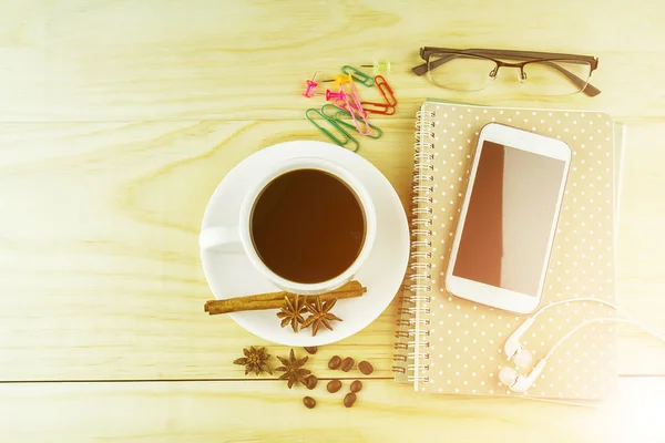Smart phone, coffee, glasses and note book on wood table backgrou — стоковое фото