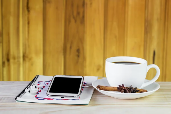 Taza de café y teléfono inteligente sobre fondo de mesa de madera . —  Fotos de Stock