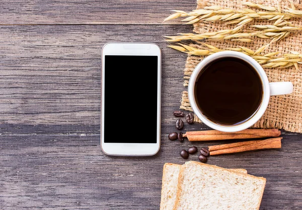 Orejas de trigo, teléfono inteligente y café con rebanada de pan —  Fotos de Stock