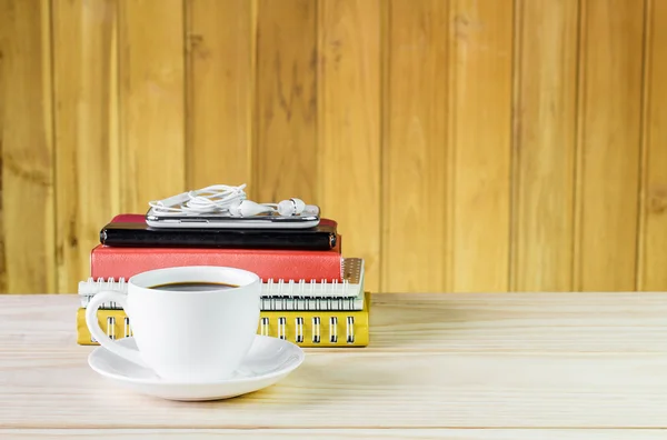 Taza de café, teléfono inteligente y libreta de notas en mesa de madera — Foto de Stock