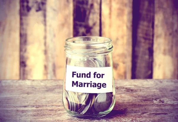 Coins in glass money jar with Fund for marriage label