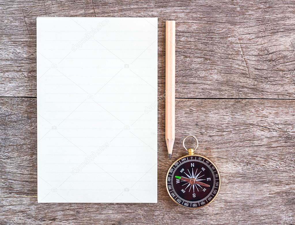 Open blank notebook with pencil and compass over a wooden backgr