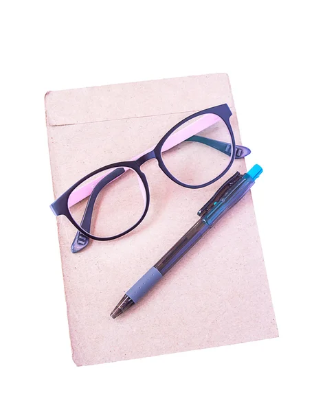 Glasögon, penna, sätta på brunt papper isolerade — Stockfoto