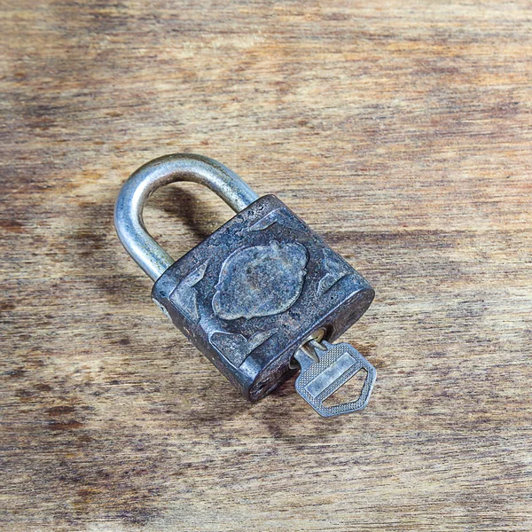 Key and rusty lock on wooden background — Stock Photo, Image