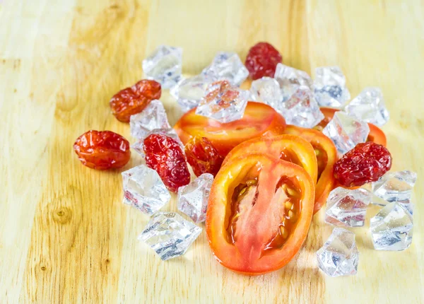 Порезать помидоры и кубики льда на деревянной тарелке — стоковое фото