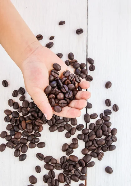 Kaffebønner i hånden på kaffebaggrund - Stock-foto