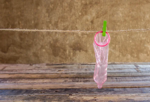 Condom hanging on line on wooden background — Stock Photo, Image