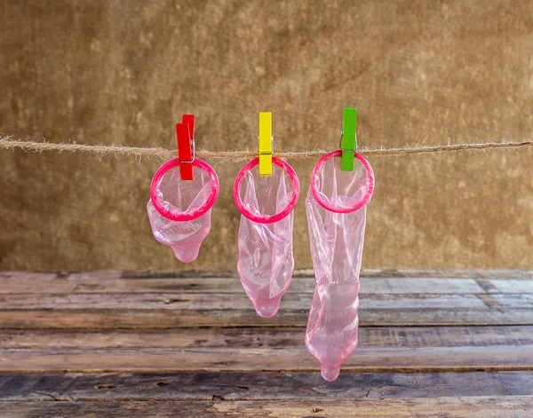 Condom hanging on line on wooden background — Stock Photo, Image