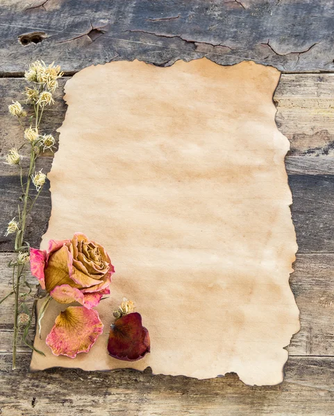 Altpapier mit getrockneter Rose auf Holzgrund — Stockfoto