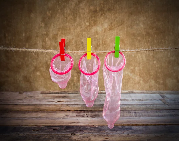Condom hanging on line on wooden background — Stock Photo, Image