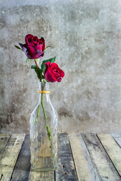 Свежая красная роза в стеклянной бутылке на деревянном фоне — стоковое фото