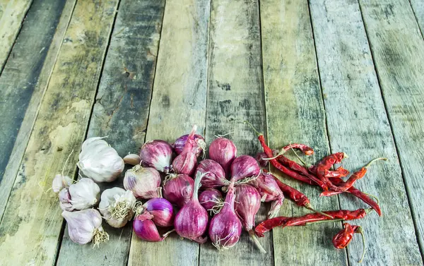 Soğan, sarımsak ve ahşap bir masa üzerinde kuru biber kapatın — Stok fotoğraf