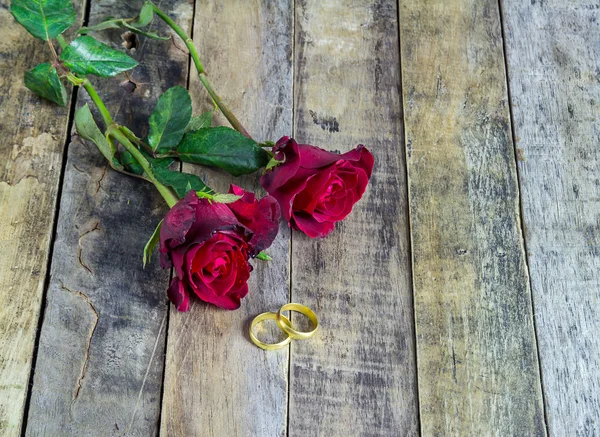 Nahaufnahme Goldring und rote Rose auf einem hölzernen Hintergrund — Stockfoto
