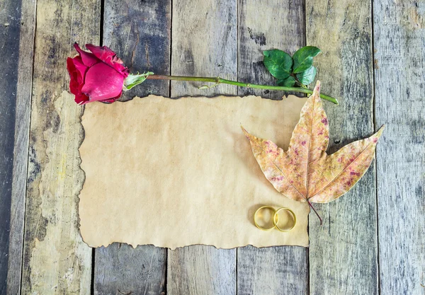 Nahaufnahme Goldring, rote Rose, trockene Blätter und altes Papier auf Holz — Stockfoto