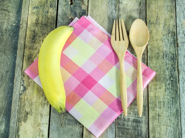 Fresh banana, spoon and fork in napkin on wooden — Stock Photo, Image