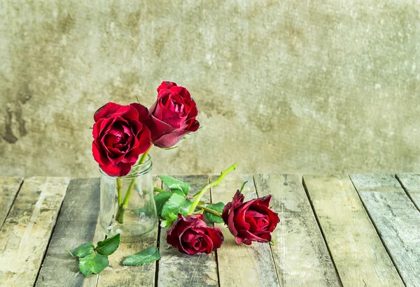 Fresh red rose in glass bottle on a wooden background — Stock Photo, Image