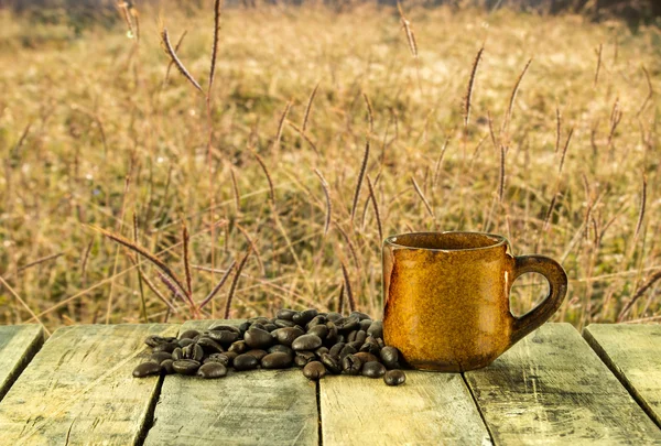 Kaffeetasse und Kaffeebohnen auf Gras Hintergrund — Stockfoto