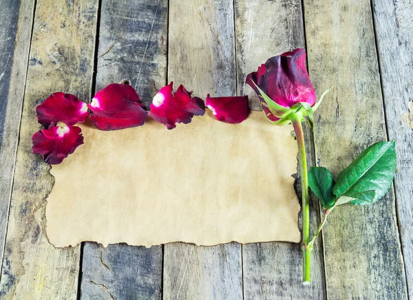 Frische rote Rose und altes Papier auf Holzgrund — Stockfoto