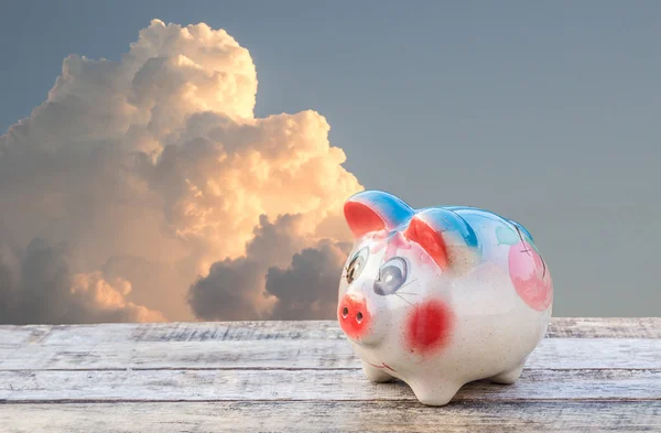 Piggy bank op houten tafel over hemel wazig achtergrond — Stockfoto