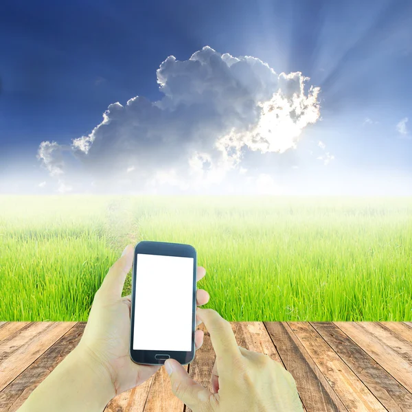 Hand holding smart phone over wooden floor — Stock Photo, Image