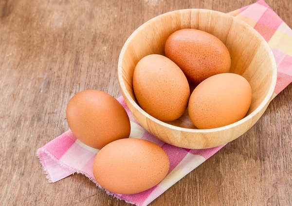 Huevos en un tazón de madera sobre la mesa —  Fotos de Stock